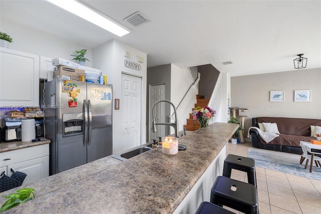 1074 NE 41st Pl, Homestead, FL 33033 - kitchen featuring stainless steel fridge with ice dispenser, open floor plan, light tile patterned floors, white cabinets, and a kitchen breakfast bar