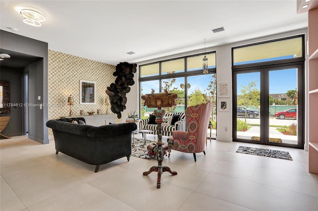 living area featuring french doors, visible vents, light tile patterned floors, an accent wall, and wallpapered walls