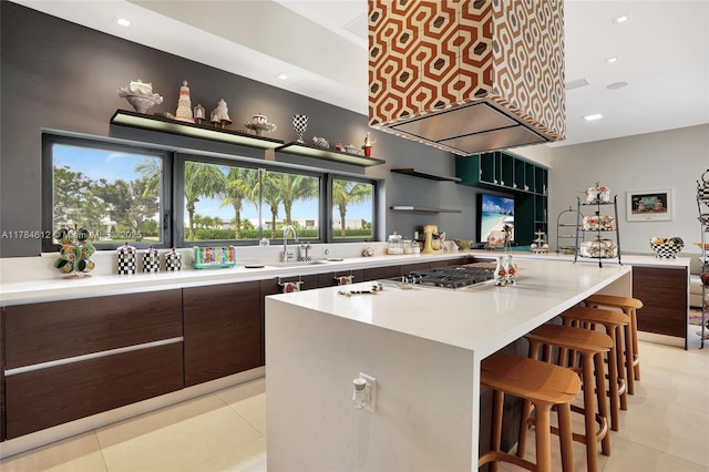 kitchen with light tile patterned flooring, light countertops, a breakfast bar area, stainless steel gas stovetop, and modern cabinets