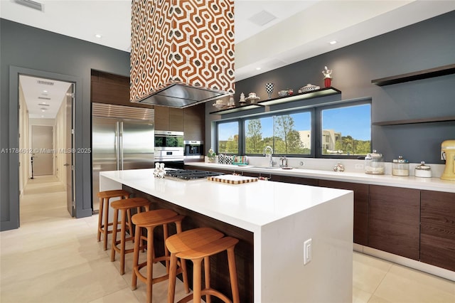 kitchen with a kitchen breakfast bar, appliances with stainless steel finishes, modern cabinets, a center island, and a sink