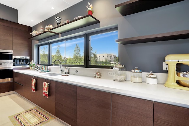kitchen with a sink, light countertops, modern cabinets, and open shelves