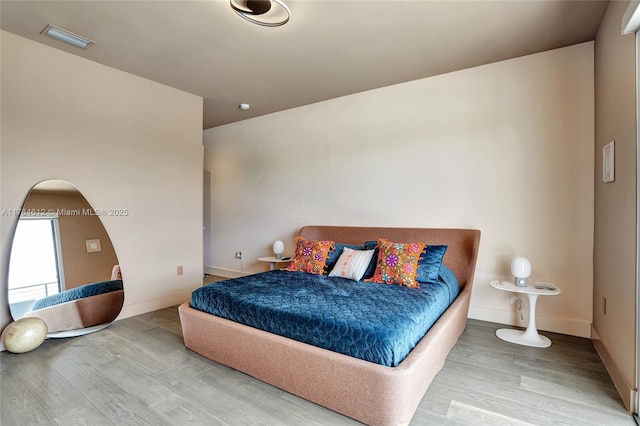 bedroom with baseboards, arched walkways, wood finished floors, and visible vents