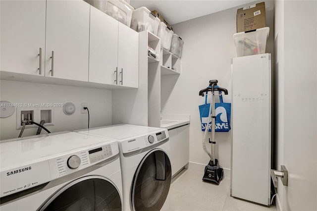 washroom featuring cabinet space, independent washer and dryer, baseboards, and light tile patterned floors