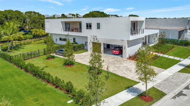 view of front of home with decorative driveway, stucco siding, a balcony, and a carport