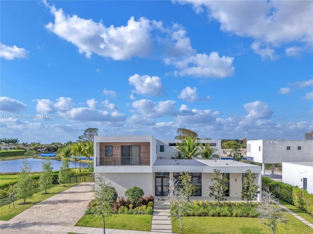 modern home featuring a water view, stucco siding, and decorative driveway