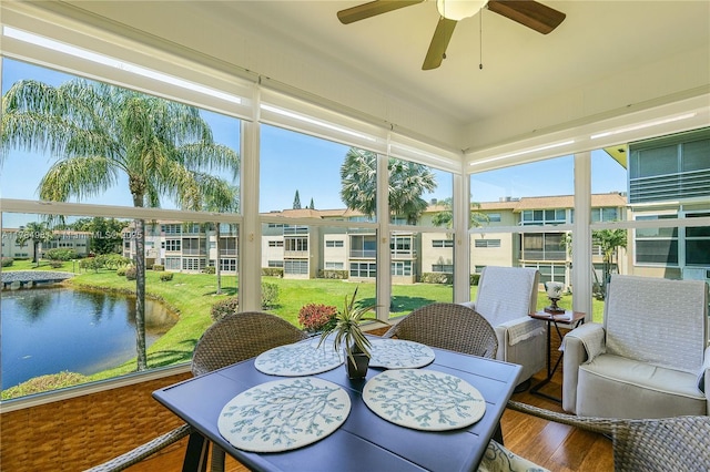sunroom / solarium featuring ceiling fan, outdoor dining area, and a water view