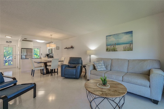 living room with a textured ceiling and light tile patterned floors