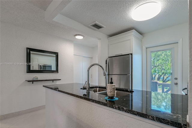 kitchen featuring dark stone countertops, visible vents, appliances with stainless steel finishes, a textured ceiling, and white cabinetry