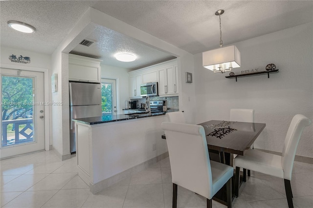 kitchen with plenty of natural light, a textured ceiling, white cabinetry, visible vents, and appliances with stainless steel finishes