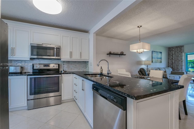kitchen featuring a textured ceiling, a peninsula, appliances with stainless steel finishes, a sink, and open floor plan