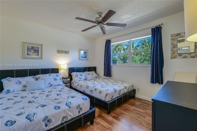 bedroom with ceiling fan, a textured ceiling, baseboards, and wood finished floors