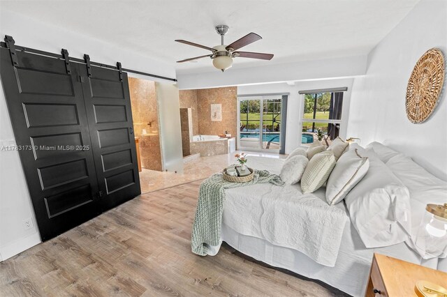 5721 Bayberry Ln, Tamarac, FL 33319 - bedroom featuring a barn door, wood finished floors, a ceiling fan, and ensuite bathroom