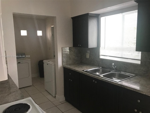 1221 W 62nd St, Hialeah, FL 33012 - kitchen with dark cabinets, separate washer and dryer, light tile patterned floors, backsplash, and a sink