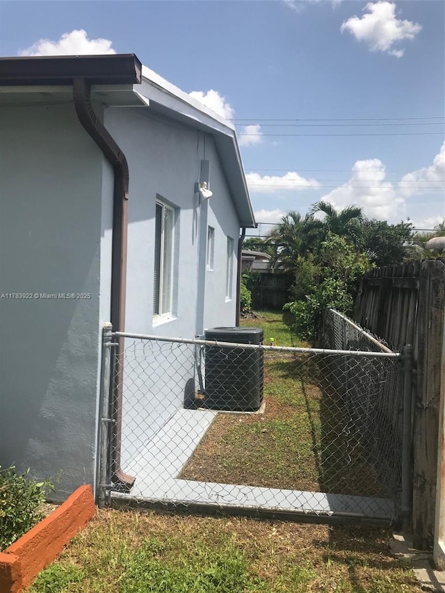 1221 W 62nd St, Hialeah, FL 33012 - view of side of property with central AC unit, stucco siding, fence, and a gate