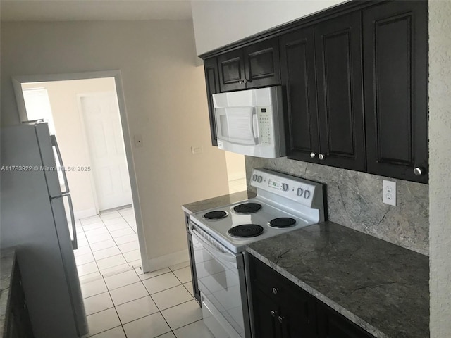 1221 W 62nd St, Hialeah, FL 33012 - kitchen featuring dark stone countertops, light tile patterned floors, white appliances, dark cabinetry, and decorative backsplash