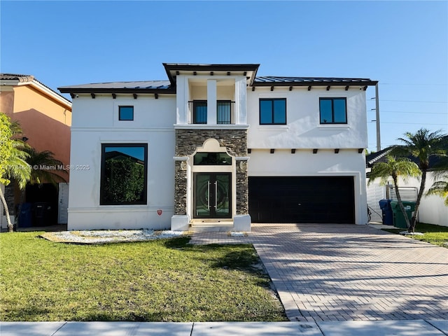 view of front facade featuring stucco siding, decorative driveway, an attached garage, a front lawn, and metal roof