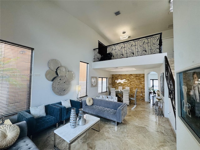 living room featuring high vaulted ceiling, arched walkways, visible vents, and plenty of natural light
