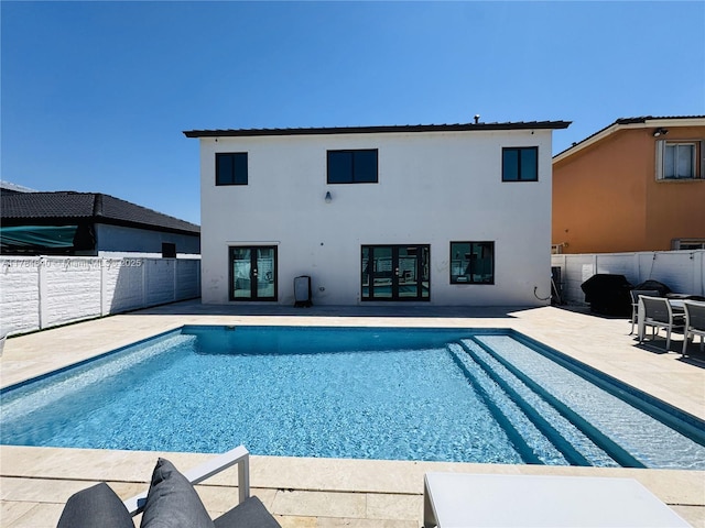 view of swimming pool with french doors, a fenced backyard, a fenced in pool, and a patio