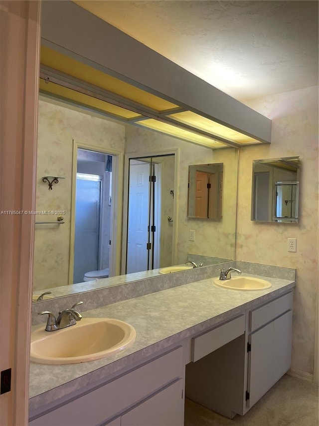 full bath with toilet, double vanity, and a sink