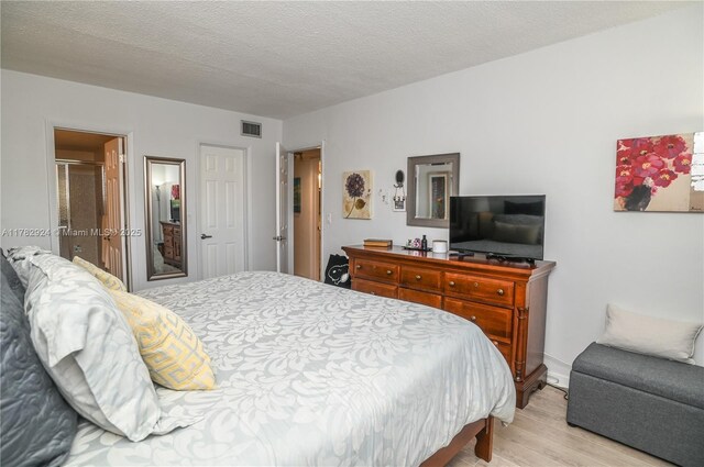 581 Blue Heron Dr Unit 112-B, Hallandale Beach, FL 33009 - bedroom featuring visible vents, light wood finished floors, and a textured ceiling