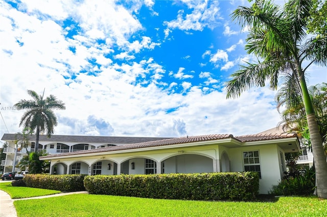 581 Blue Heron Dr Unit 112-B, Hallandale Beach, FL 33009 - view of front of home featuring a tile roof, a front lawn, and stucco siding