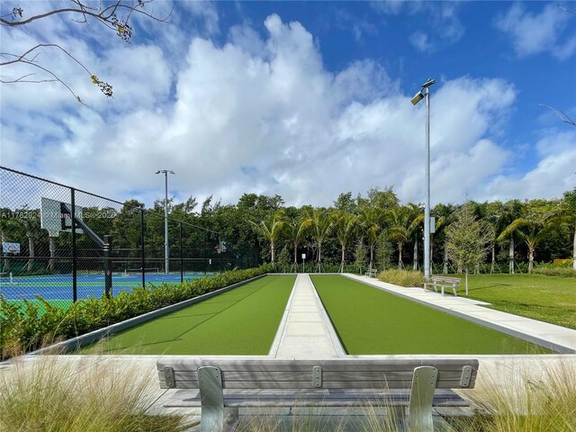 581 Blue Heron Dr Unit 112-B, Hallandale Beach, FL 33009 - surrounding community featuring a tennis court, fence, and a lawn