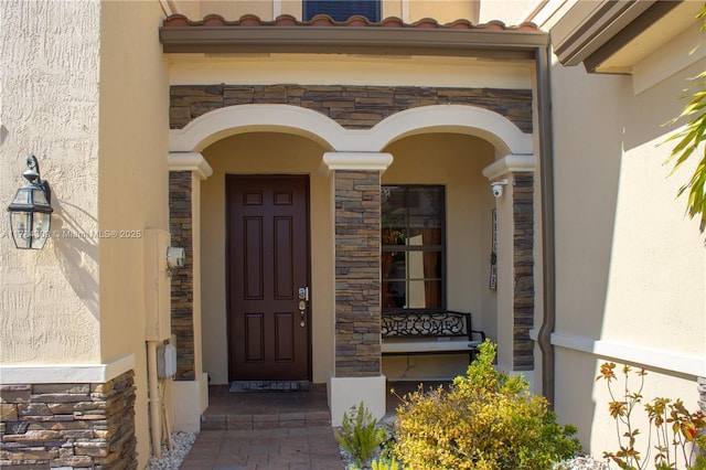 entrance to property featuring stone siding and stucco siding