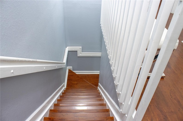 staircase featuring hardwood / wood-style floors and baseboards