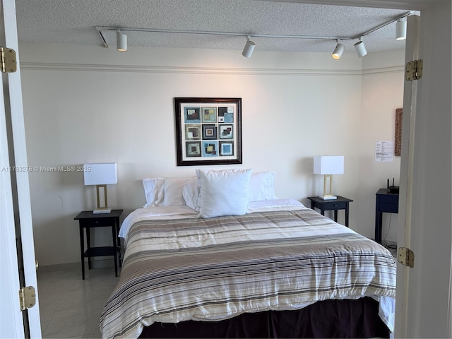 bedroom with rail lighting and a textured ceiling