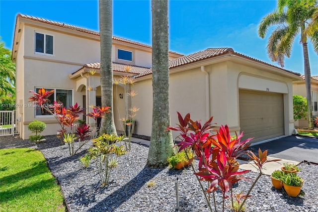 mediterranean / spanish home with a tile roof, an attached garage, driveway, and stucco siding