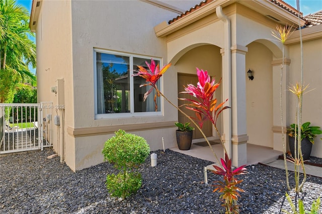 property entrance featuring a tile roof and stucco siding