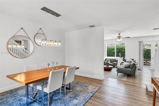 dining area with wood finished floors, baseboards, a ceiling fan, and visible vents