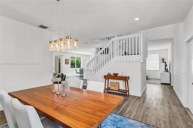 dining space featuring visible vents, an inviting chandelier, recessed lighting, stairway, and wood finished floors