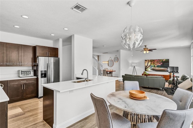 kitchen with stainless steel fridge, light countertops, visible vents, light wood finished floors, and a sink