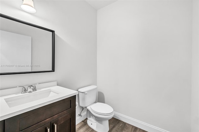 bathroom with toilet, baseboards, vanity, and wood finished floors