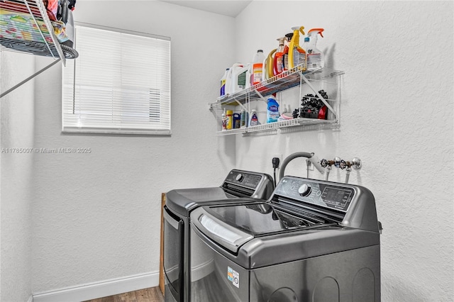 laundry room with laundry area, wood finished floors, washer and dryer, a textured wall, and baseboards