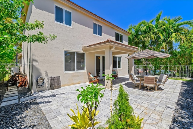 back of house with a patio area, stucco siding, a tiled roof, and fence