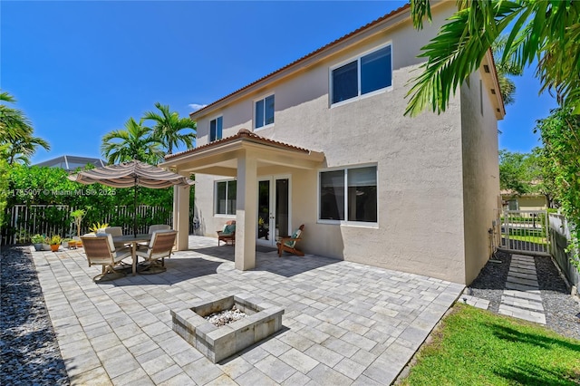 back of property featuring a fire pit, a patio area, fence, stucco siding, and french doors