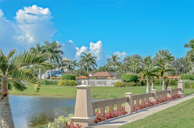 view of community featuring a yard, fence, and a water view