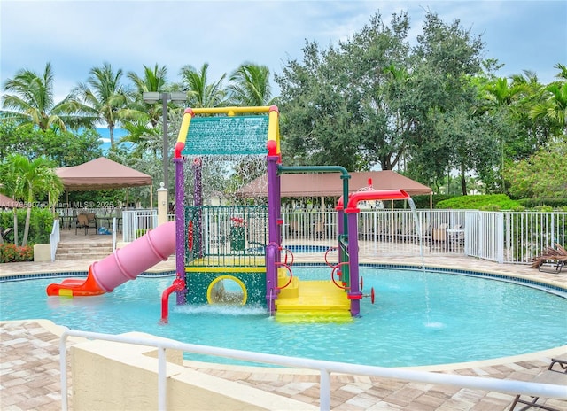 community jungle gym featuring a water play area, a community pool, and fence