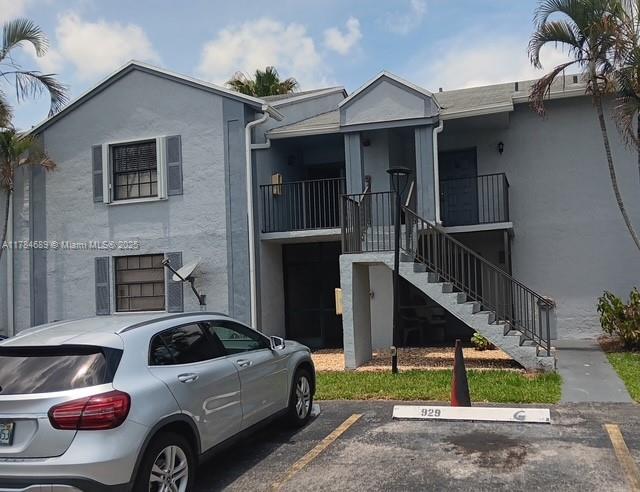 townhome / multi-family property featuring stucco siding, uncovered parking, and stairway