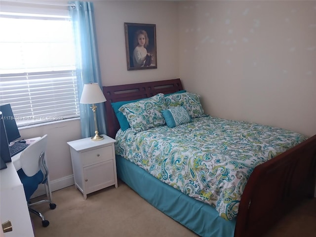 bedroom featuring light carpet and an office area