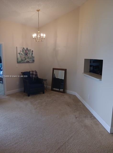 living area with a chandelier, carpet floors, baseboards, and vaulted ceiling