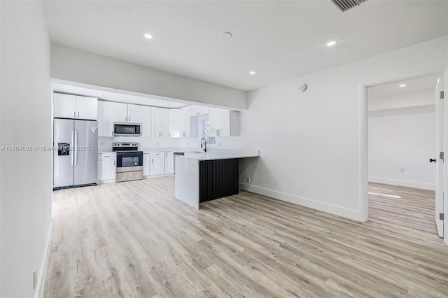 221 SW 28th Ter, Fort Lauderdale, FL 33312 - kitchen with light countertops, light wood-style floors, a peninsula, and stainless steel appliances