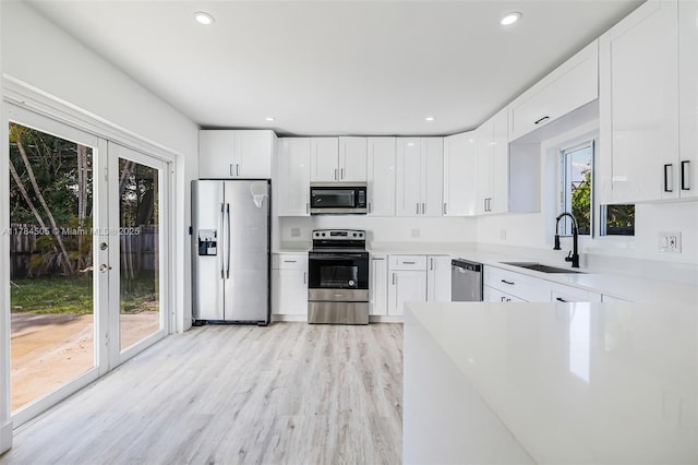 221 SW 28th Ter, Fort Lauderdale, FL 33312 - kitchen with light wood-type flooring, white cabinetry, a sink, and appliances with stainless steel finishes