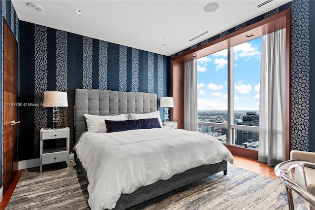 bedroom with wallpapered walls and wood finished floors