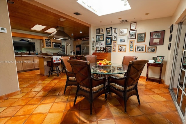 dining area with a skylight, light tile patterned floors, and baseboards