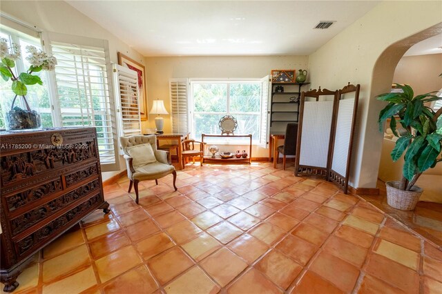 living area featuring arched walkways, baseboards, and light tile patterned flooring