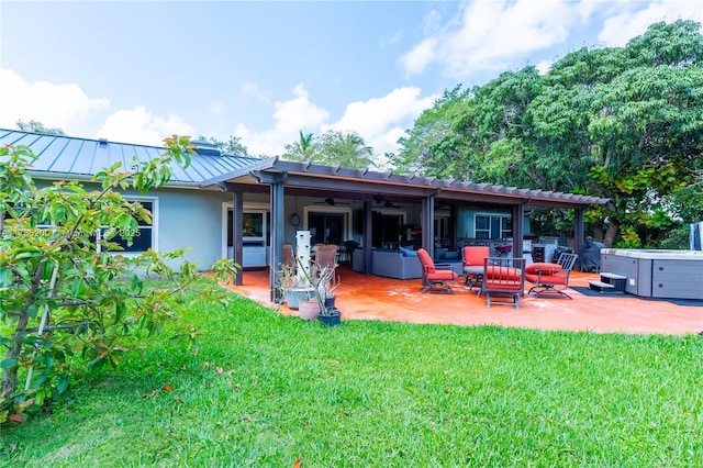 rear view of house featuring a standing seam roof, a ceiling fan, a patio, a lawn, and an outdoor hangout area