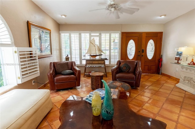 living area featuring a ceiling fan, tile patterned flooring, and baseboards